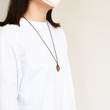 フゴッペ洞窟の人型デザインが刻印された陶製ペンダント 着用イメージの写真