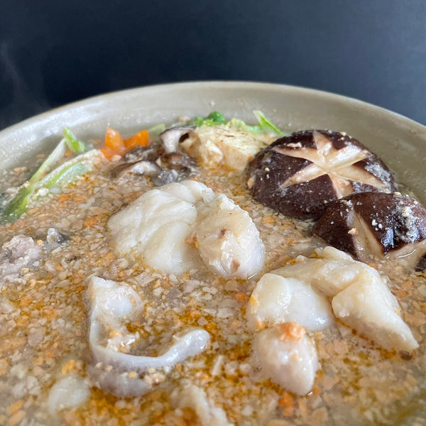 菊鮨の北海道余市あんこう鍋の調理例。あん肝の粒が浮かぶ味噌仕立てのスープに、白いアンコウの身と骨、しいたけと野菜が入っている写真
